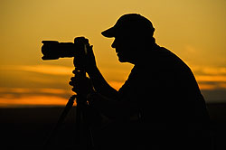 Silhouette of photographer with camera at sunset