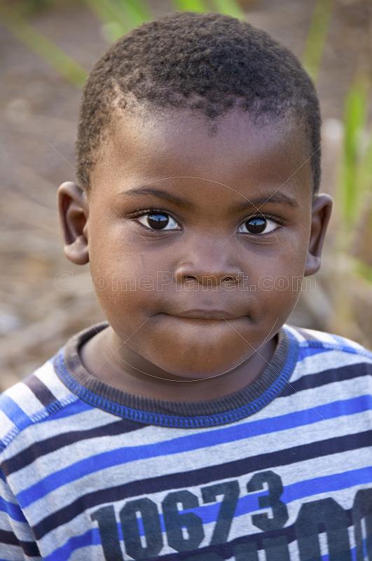 Young Gabonese boy in a white and blue striped sweat shirt.