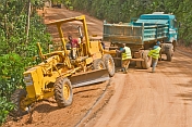 A heavy truck helps to pull a stranded grader out of trouble on a jungle logging road.