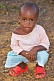 Image of Young Gabonese girl with short hair in a light pink shirt and red shoes.