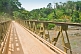 A steel Bailey bridge crosses the Ogooue River amidst jungle and plantations.