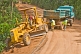 Image of A heavy truck helps to pull a stranded grader out of trouble on a jungle logging road.