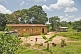 Image of Mud-brick house with corrugated iron roof in jungle clearing.