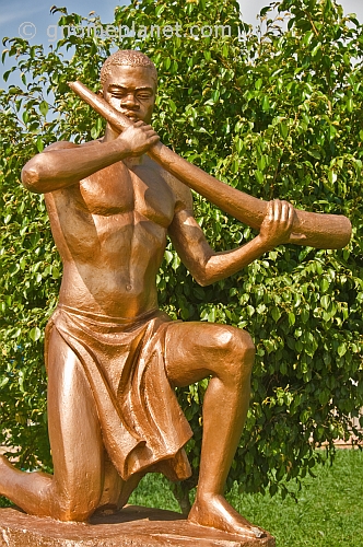 Bronze painted statue of man in loincloth holding a tusk of ivory.