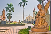 Golden statues of angel and Virgin Mary in front of the white and gray Roman Catholic church.