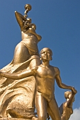 Bronze painted statue of woman in loincloth with three children.