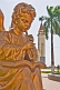Image of Golden statue of angel playing music in front of the white stucco Roman Catholic church.