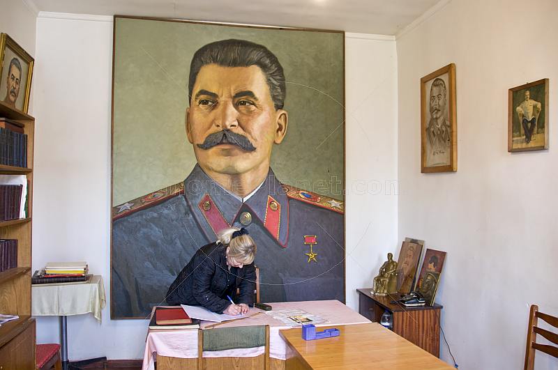 The Director of the Joseph Stalin museum prepares the visitors book in front of a huge portrait of Uncle Joe.