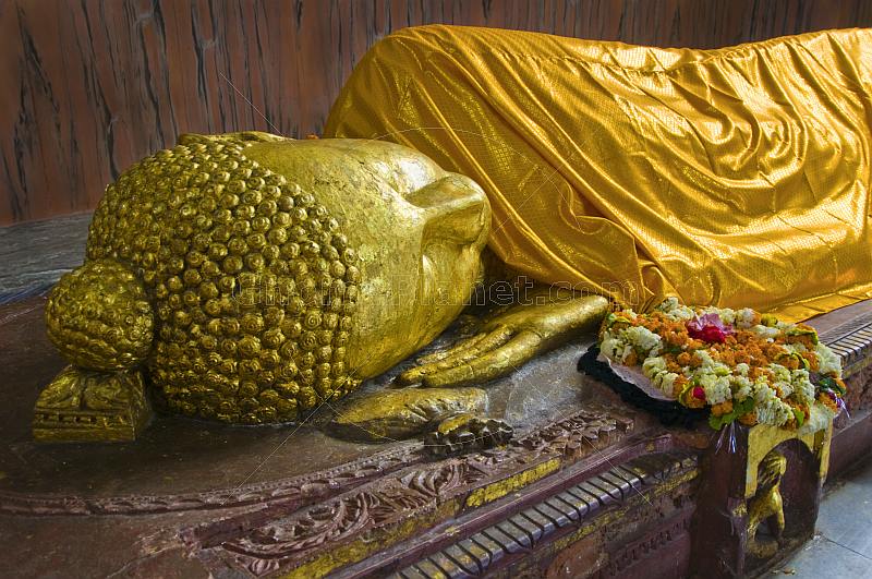 A floral wreath is placed next to the 6m recumbent statue of the dying Buddha in the Parinivarna Temple.