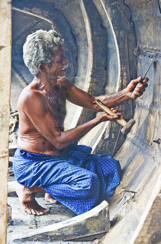 An old man repairs his fishing boat.