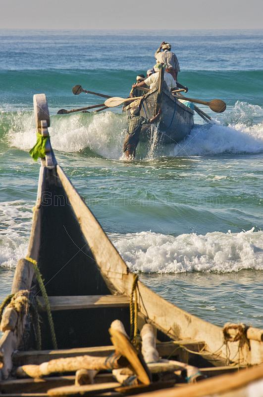 Fishermen battle the waves to launch their boat at Kovalam Beach.