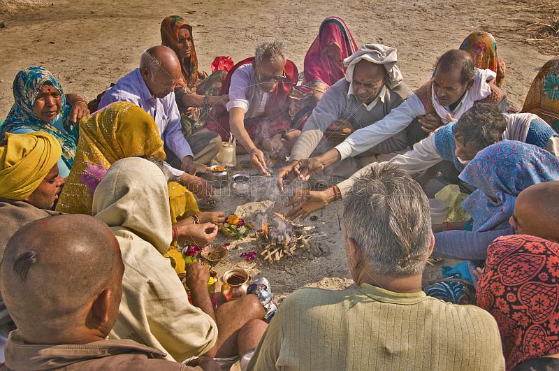 Family group perform Hindu Fire Ceremony by Ganges River at Kumbh Mela festival.