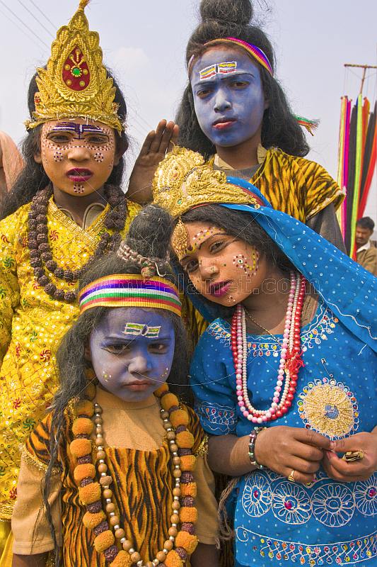 Four Indian children in colorful clothes and face paint decorated as Hindu Gods.