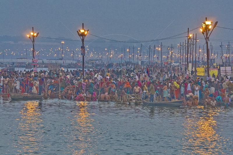 Mass Hindu pilgrims at crowded Ganges Yamuna bathing ghats at dawn.