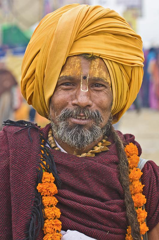 Smiling Hindu Holy Man with saffron-colored turban and marigold flower garlands.