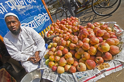 Muslim fruit-seller selling apples on the pavement.