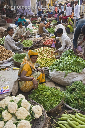 Traders at a busy vegetable markets squat to sell fruit, vegetables, herbs, and fresh spices.