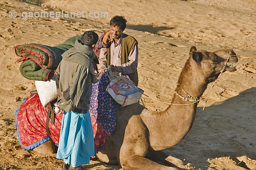 Two camel drivers chat as they prepare a camel for the days ride.