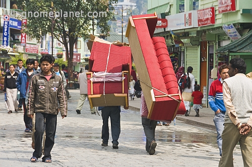 Porters carry a three-piece suite of furniture along the pedestrianised M.G. Marg.