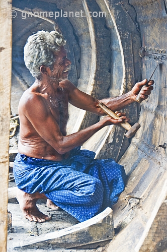 An old man repairs his fishing boat.
