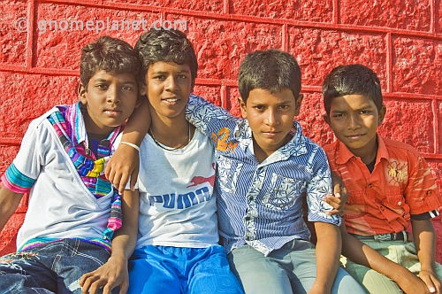Four Indian schoolboys in colored shirts pose for their photograph.