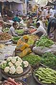 Traders at a busy vegetable markets squat to sell fruit, vegetables, herbs, and fresh spices.