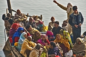 Pilgrims crowd on to a boat to cross the Ganges River.