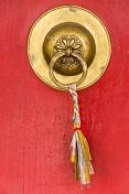 Brass door handle on a red monastery door.