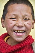 Smiling Buddhist monk in red jersey.