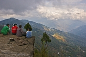 Four boys at the Sangachoeling Monastery look over a stormy valley as the sun breaks through the clouds.