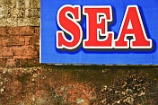 Blue sign with red letters on a brick wall.