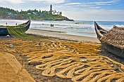 Fishermen dry their nets next to their boats on the beach.