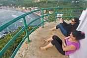 Two young Indian women enjoy the view of Kovalam Beach from the top of the Vizhinjam Lighthouse tower.