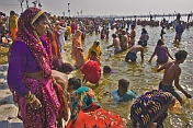 Crowds of Hindu pilgrims bathe in Ganges river shallows on Basant Panchami Snana.