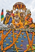 Large group of Hindu holy men on roof of flower decorated jeep.