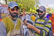 Two young men sell false beards and moustaches to Kumbh Mela pilgrim visitors.