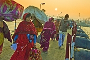 Pilgrims cross Ganges river pontoon bridge at dawn to join Kumbh Mela festival.