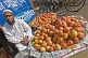 Image of Muslim fruit-seller selling apples on the pavement.