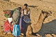 Image of Two camel drivers chat as they prepare a camel for the days ride.