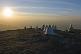 Image of A group of Jain holy men meditate as the sun sets over the mountains.