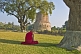 Image of Buddhist monk sits in silent meditation before the 5thC Dhamekh Stupa at Sarnath.