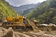Image of An Indian Army bulldozer deals with a sudden landslide that is blocking a mountain road.