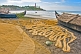 Image of Fishermen dry their nets next to their boats on the beach.