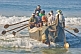 Image of Fishermen battle the waves to launch their boat at Kovalam Beach.