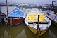 Image of Deserted blue and yellow rowing boats wait for hire by Sangam Hindu pilgrims.