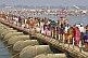 Image of Long lines of Indian Hindu pilgrims cross pontoon bridge over Ganges river.