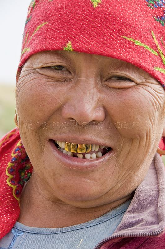 Kazakh woman with red headscarf and gold teeth.