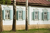 Russian-style painted Cottage with shutters, decorative windows and surrounding Birch Trees.