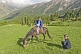 Image of A Kyrgyz Horseman waits with his farmer friend as his horse crops the grass of the Altyn Arashan Mountains.
