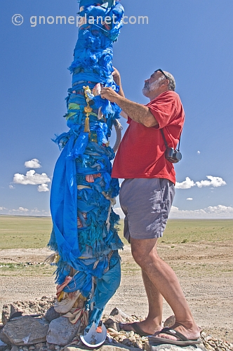 Tying a blue prayer scarf on an 'Ovoo', a Mongolian Shamanistic cairn for travellers.